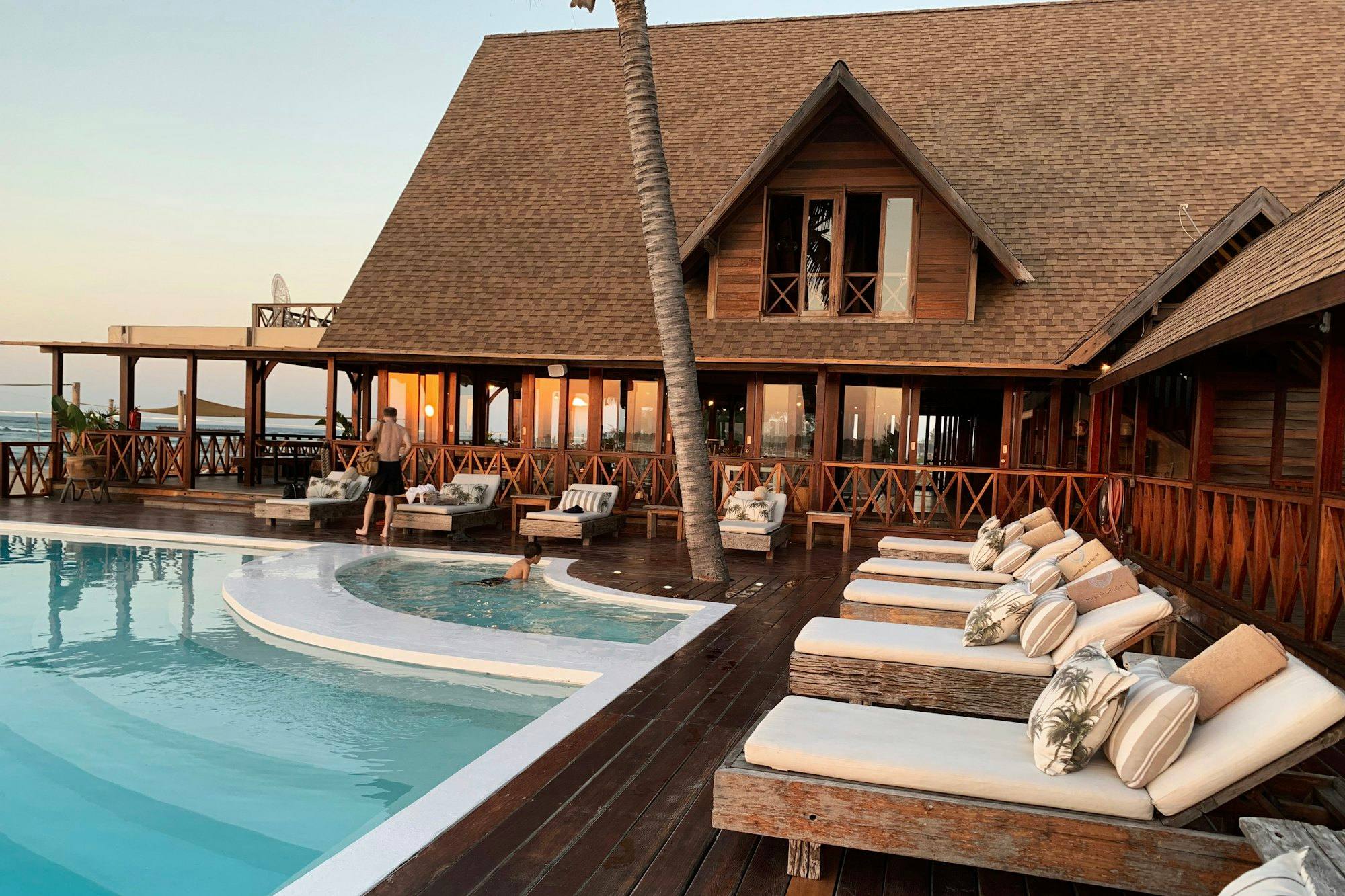 A wooden lodge with a pool at golden hour